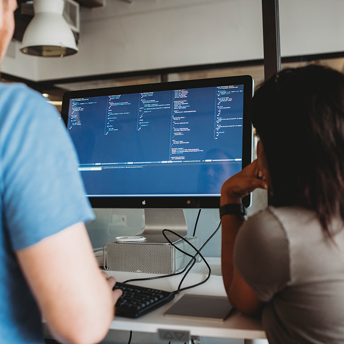Developers working together at a desk pairing on a problem